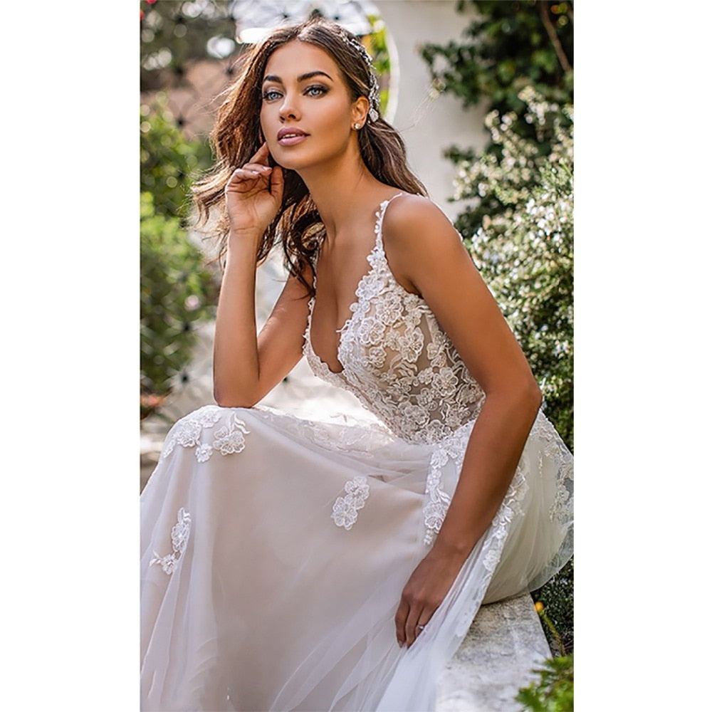 Vestido de novia corte A, tipo boho, con aplicaciones florales 3D y tirantes.